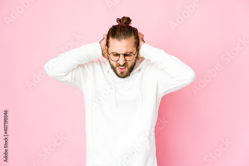 Young man with long hair look covering ears with fingers, stressed and desperate by a loudly ambient.