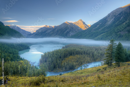 A beautiful lake in a mountain valley. Fog flies over the lake. Photo from above.