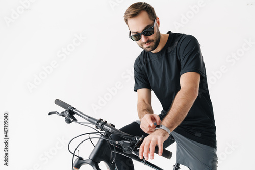 Focused young man using smartwatch while riding his bicycle