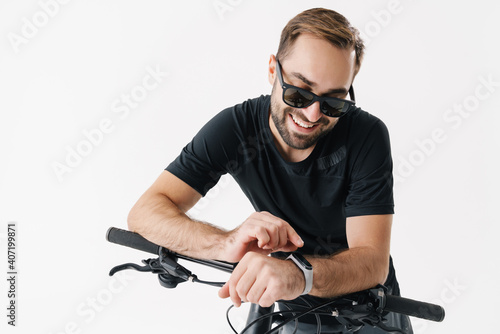 Smiling young man using smartwatch while riding his bicycle