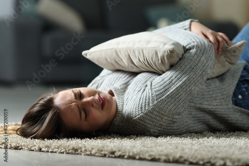 Sad teen complaining embracing pillow on the floor at home