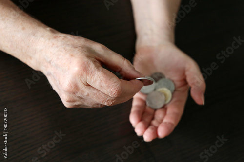 Elderly woman counts a coins, wrinkled female hands with metal money closeup. Concept of poverty, pension payments, pensioner