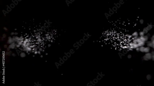 Sprinkle salt or glitter in slowmotion down into black background.