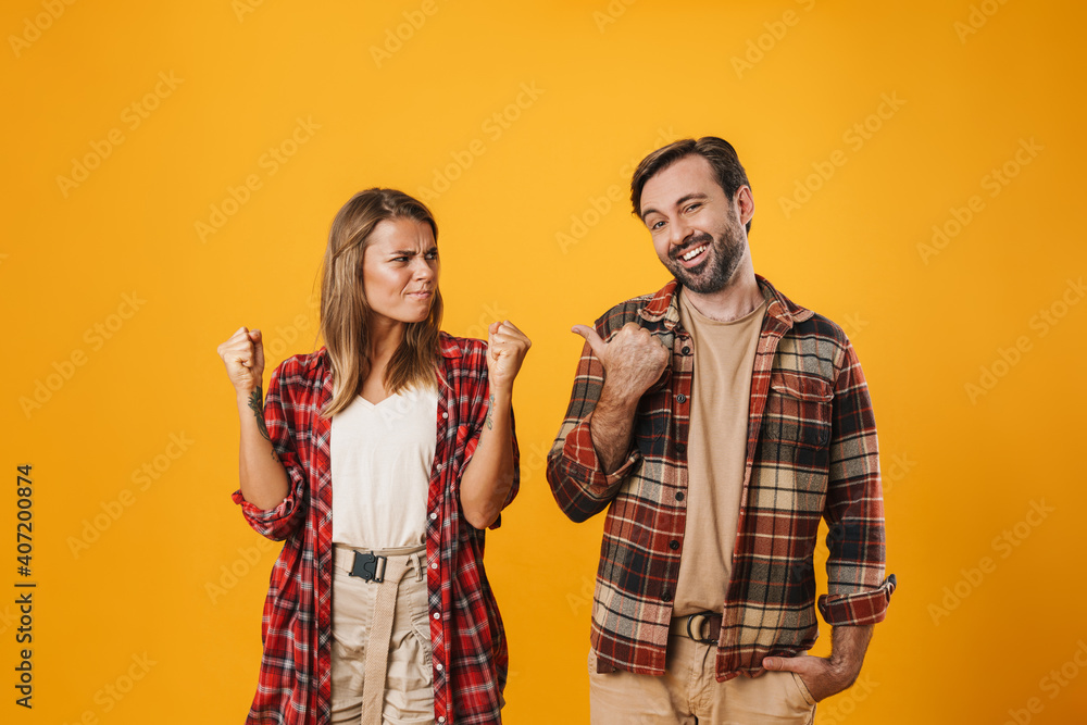 Smiling unshaven man pointing finger at irritated blonde woman Smiling unshaven man pointing finger at irritated blonde woman