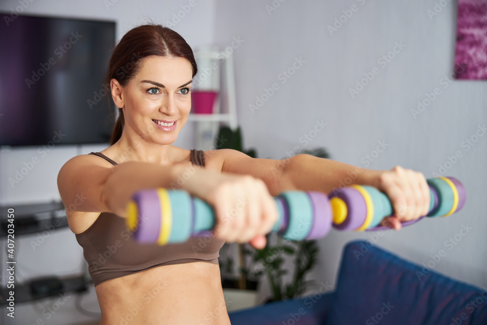 Happy young woman enjoying upper body workout indoors Happy young woman enjoying upper body workout indoors