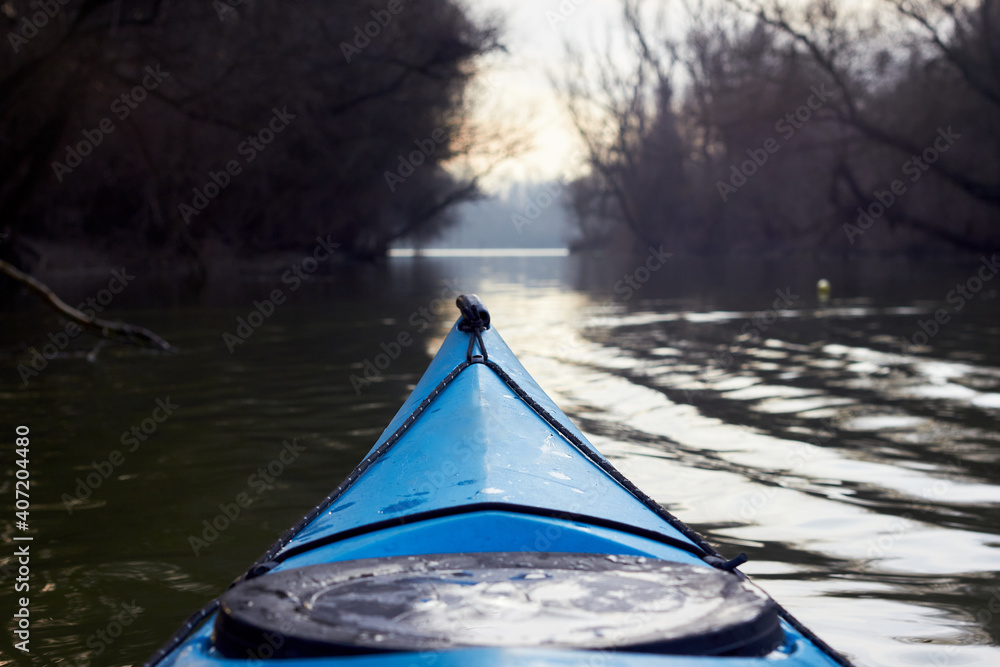 Fototapeta premium Bow (prow) of blue kayak in winter or early spring river. Winter kayaking