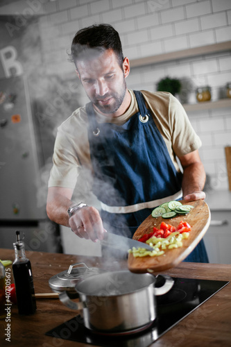 Attractive man cooking in modern kitchen. Handsome man preparing food.
