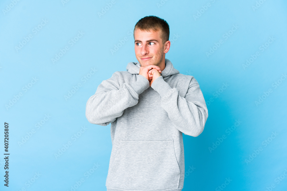 Young caucasian handsome man keeps hands under chin, is looking happily aside. Young caucasian handsome man keeps hands under chin, is looking happily aside.