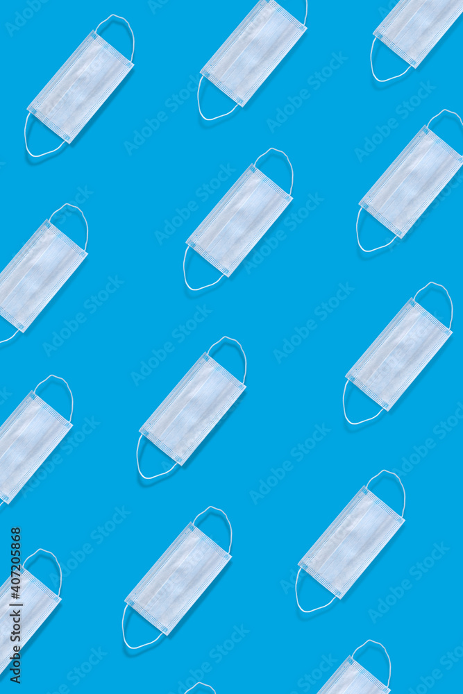 Many medical masks on a blue background cover the mouth and nose to protect against viruses and bacteria. Epidemic concept. Regular pattern, flat lay. Many medical masks on a blue background cover the mouth and nose to protect against viruses and bacteria. Epidemic concept. Regular pattern, flat lay.