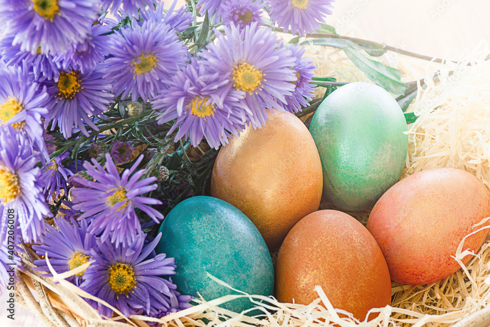 Colorful eggs in a basket with a bouquet of flowers