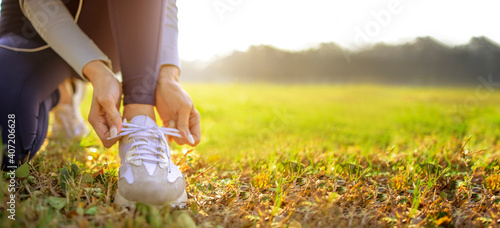 Slika na platnu young woman runner tying her shoes preparing for a jog outside at morning