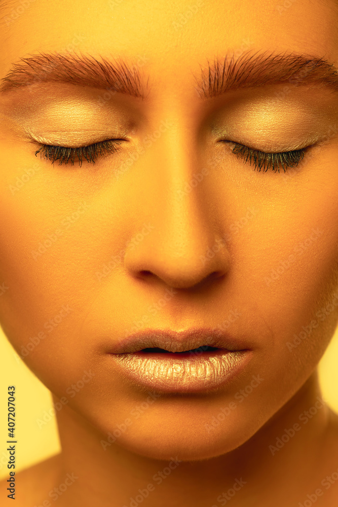 Close up face. Beautiful east woman's portrait isolated on yellow studio background in neon, monochrome. Female model. Concept of human emotions, facial expression, sales, ad, fashion and beauty. Close up face. Beautiful east woman's portrait isolated on yellow studio background in neon, monochrome. Female model. Concept of human emotions, facial expression, sales, ad, fashion and beauty.