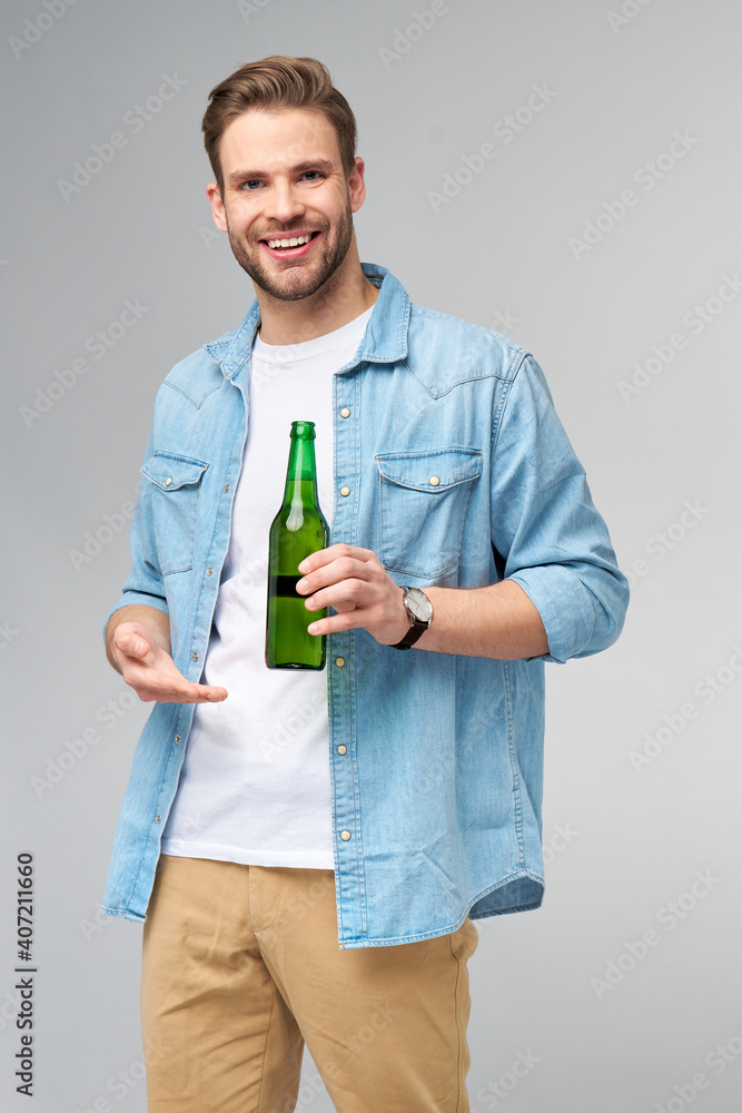 Young Man holding wearing jeans shirt holding Bottle of beer standing over Grey Background Young Man holding wearing jeans shirt holding Bottle of beer standing over Grey Background