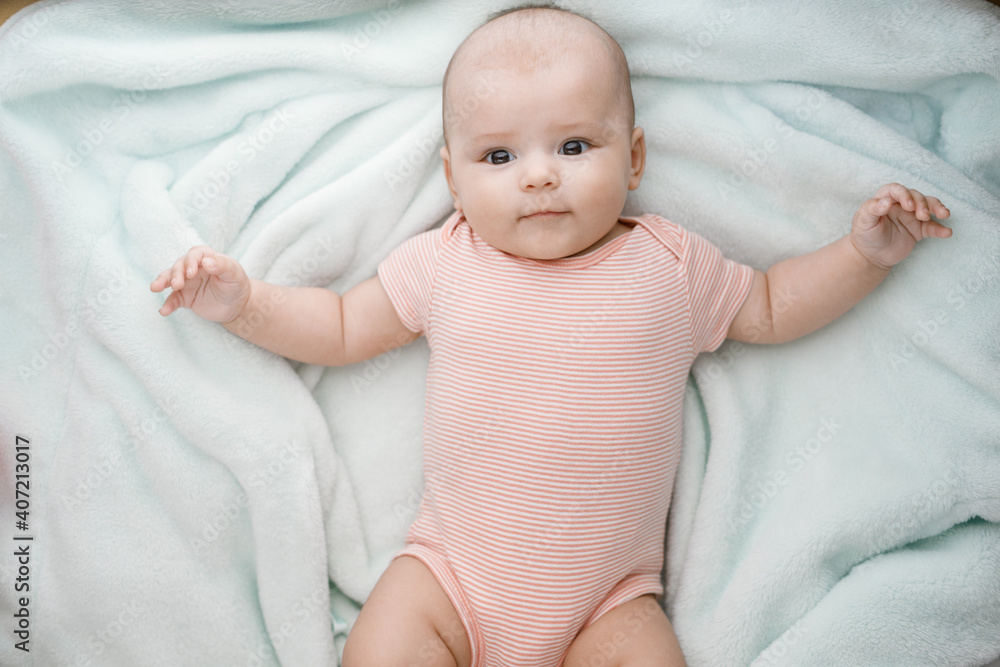 Adorable baby in sunny bedroom. Newborn baby is resting in bed with a warm soft blanket. Family morning at home. Smiling child looking at camera. Adorable baby in sunny bedroom. Newborn baby is resting in bed with a warm soft blanket. Family morning at home. Smiling child looking at camera.