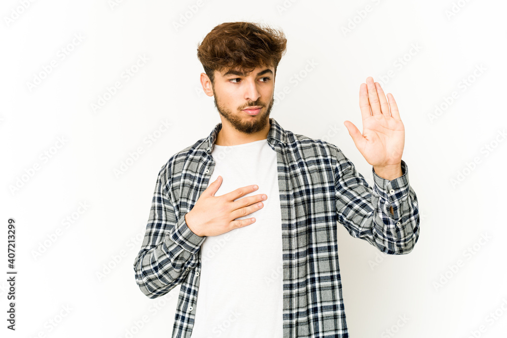 Young arab man on white background taking an oath, putting hand on chest. Young arab man on white background taking an oath, putting hand on chest.