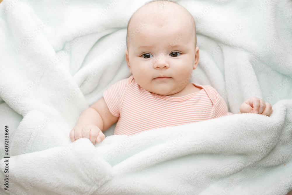 Adorable baby in sunny bedroom. Newborn baby is resting in bed covered warm soft blanket. Family morning at home. Smiling child looking at camera. Adorable baby in sunny bedroom. Newborn baby is resting in bed covered warm soft blanket. Family morning at home. Smiling child looking at camera.