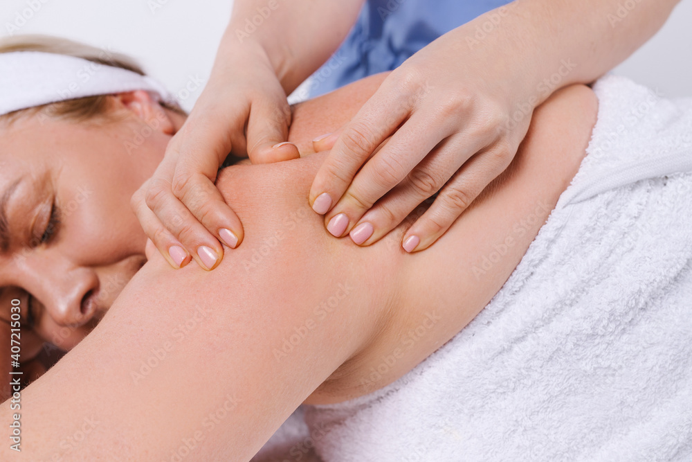 Enlarged photo where the hands of the masseur massage the back of a woman with an inverted white towel. Enlarged photo where the hands of the masseur massage the back of a woman with an inverted white towel.