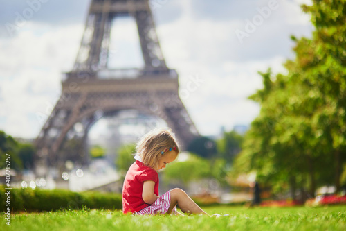 Unhappy and gloomy toddler girl sitting on the grass near the Eiffel tower in Paris © Ekaterina Pokrovsky