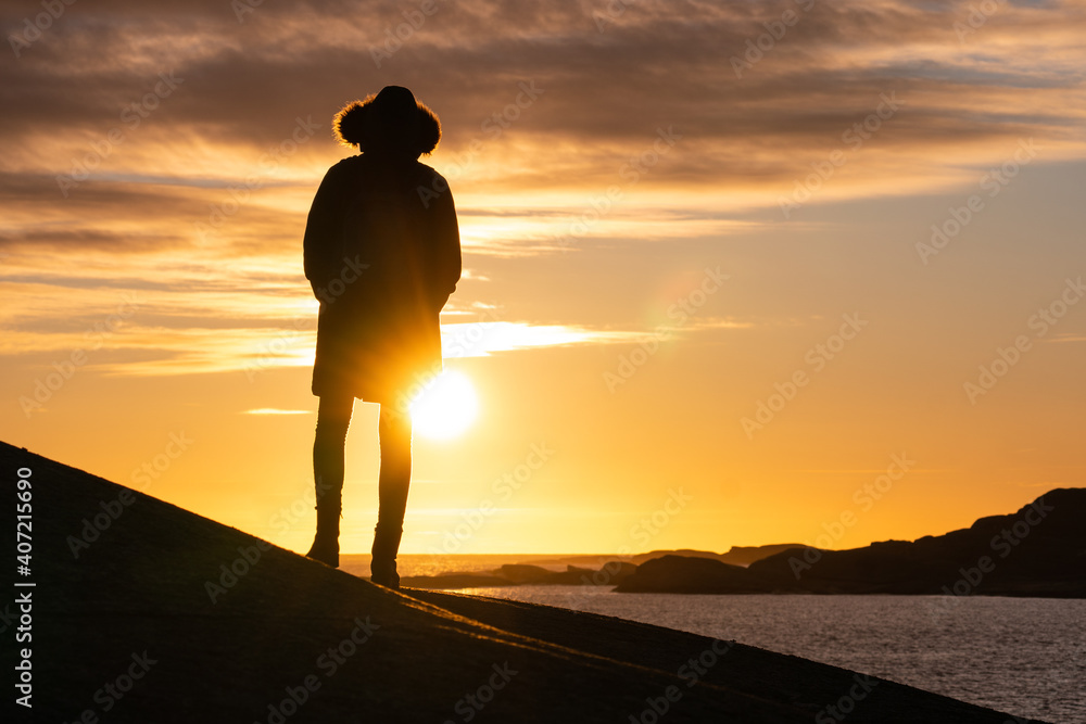 silhouette of a person walking on the beach at sunset in Norway