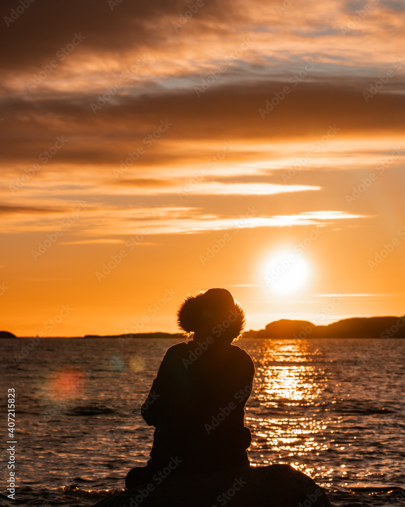 silhouette of a person walking on the beach at sunset in Norway