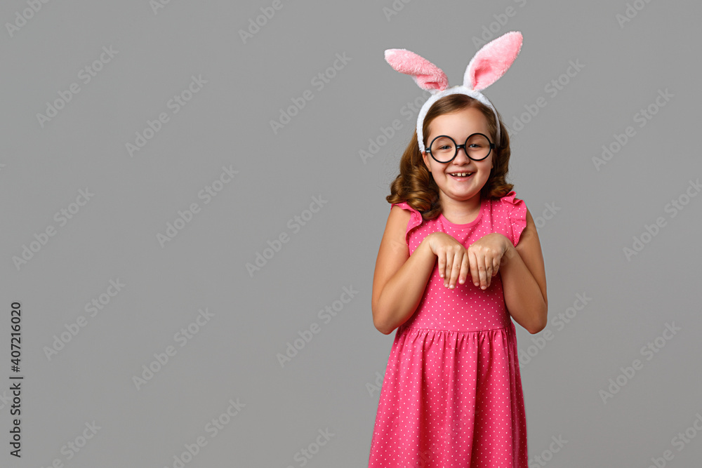 Funny cheerful little girl wearing glasses and Easter bunny ears. Child on a gray background. Funny cheerful little girl wearing glasses and Easter bunny ears. Child on a gray background.