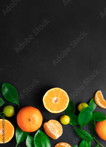 Tangerines or clementines with leaves on a black background. Top view with copy space. © Sasha