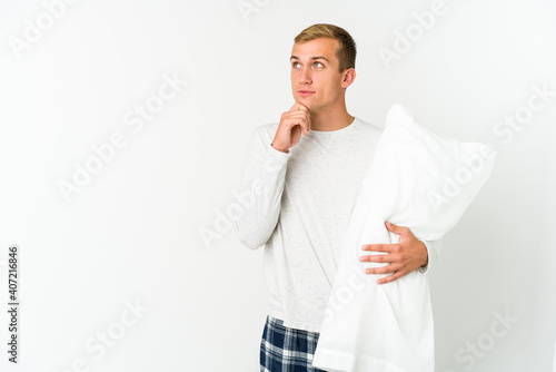 Young caucasian man going to sleep isolated on white background © Asier