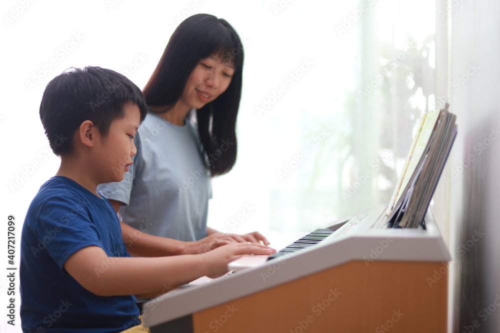 Asian mother teaching her son playing electronic organ at home. Asian mother teaching her son playing electronic organ at home.