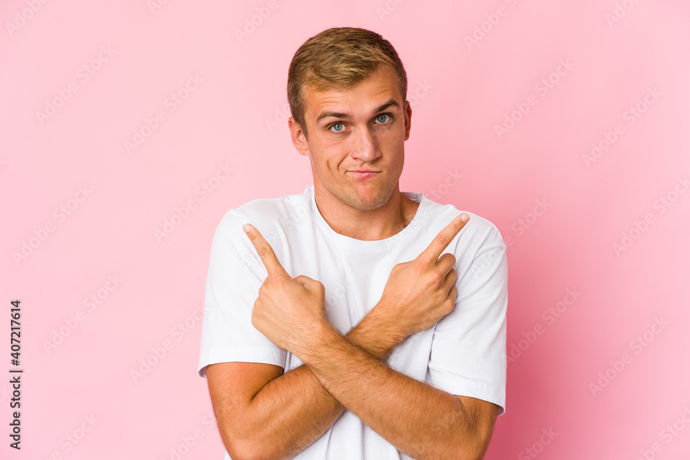 Young caucasian handsome man points sideways, is trying to choose between two options. Young caucasian handsome man points sideways, is trying to choose between two options.