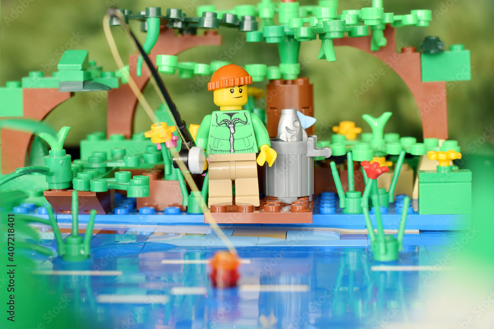 Plastik lego minifigure fisher with rod by the lake. Editorial illustrative  image of hobby fishing. Studio shot. Stock Photo