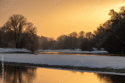 a winter landscape at sunset with fresh powder snow at the isar  munich  germany