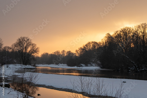 a winter landscape at sunset with fresh powder snow at the isar, munich, germany