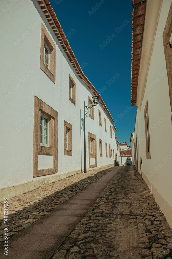 Facade of old whitewashed houses and cute windows in cobblestone alley, on a sunny day at Marvão. An amazing medieval fortified village in Portugal.