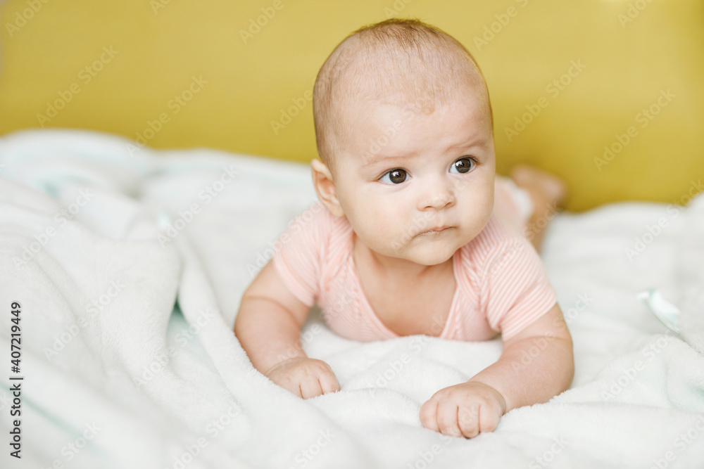 Adorable baby in sunny bedroom. Newborn baby is resting in bed with a warm soft blanket. Family morning at home. Smiling child looking at camera. Adorable baby in sunny bedroom. Newborn baby is resting in bed with a warm soft blanket. Family morning at home. Smiling child looking at camera.