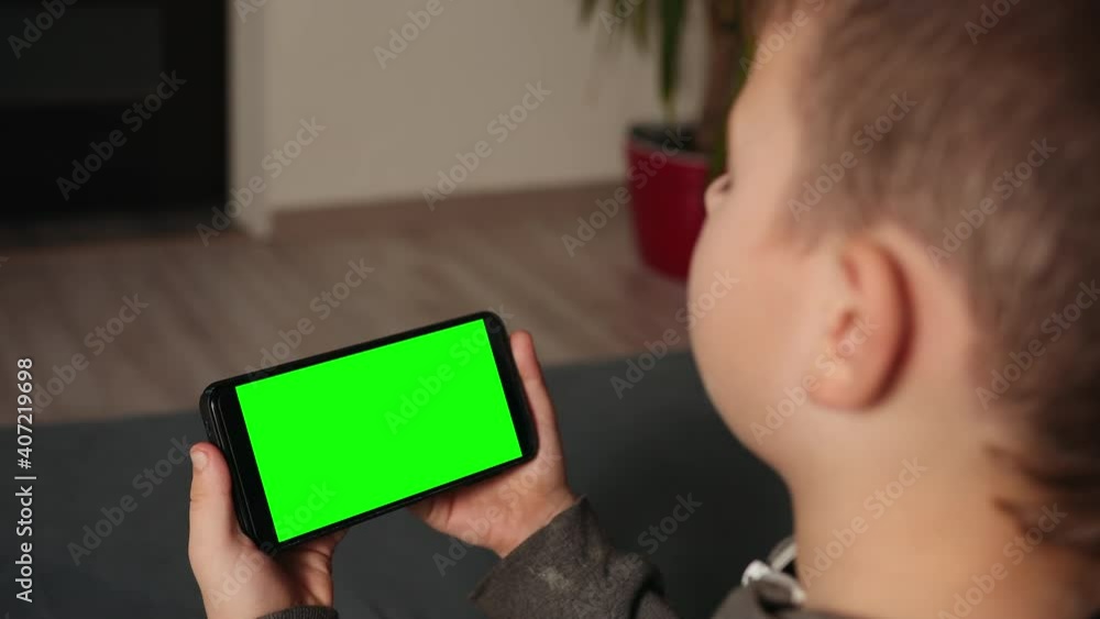 Child with digital gadget. Mobile application for a kid. Young boy uses cell phone. Happy lad talking by video connection. Green screen, keying Child with digital gadget. Mobile application for a kid. Young boy uses cell phone. Happy lad talking by video connection. Green screen, keying