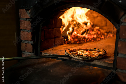 Making pizza on wood fire. Pizza is moving out at peel from hot slove 