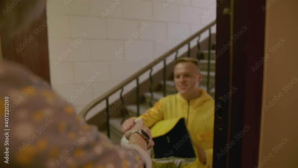 Сustomer receives ordered food from restaurant, from the hands of a local food delivery courier. Сustomer receives ordered food from restaurant, from the hands of a local food delivery courier.