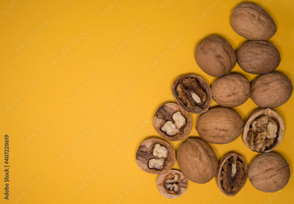 Obraz premium Walnuts on mustard background. Walnuts whole and open. Yellow background