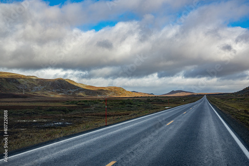 Straight road through a sparse landscape in Norway