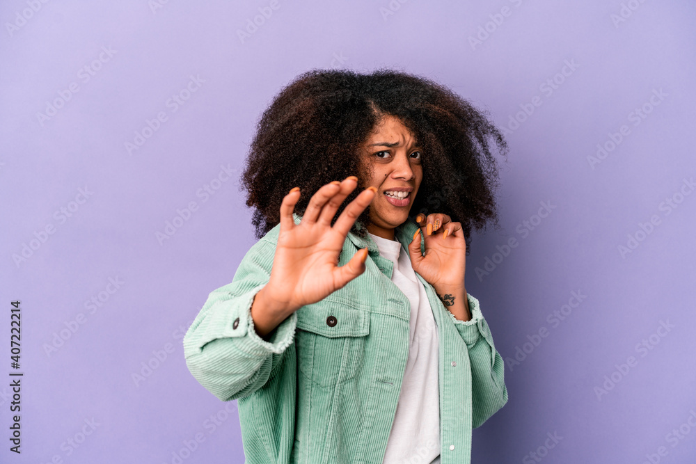 Young african american curly woman isolated on purple background being shocked due to an imminent danger Young african american curly woman isolated on purple background being shocked due to an imminent danger