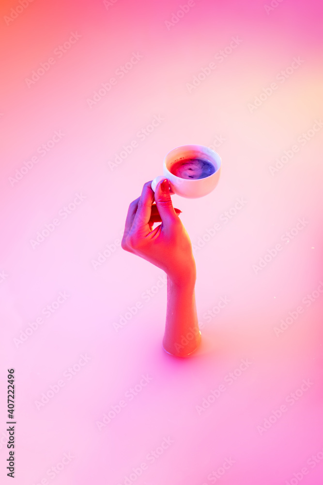 Tasty honey tea. Close up female hand gesturing from the milk bath with soft white glowing in neon light. Copyspace for advertising. Holding cup of hot coffee, espresso. Modern neoned colors.