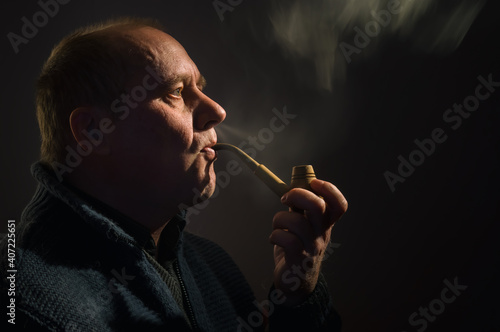 Nice portrait of a Caucasian man with tobacco pipe (side view, low key)