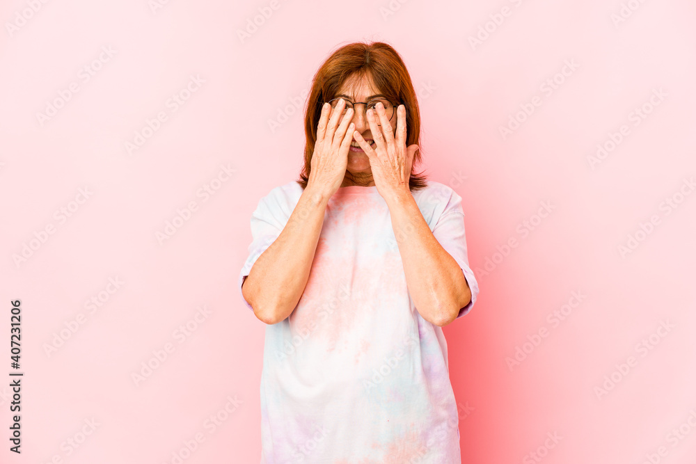 Senior caucasian woman isolated blink at the camera through fingers, embarrassed covering face. Senior caucasian woman isolated blink at the camera through fingers, embarrassed covering face.