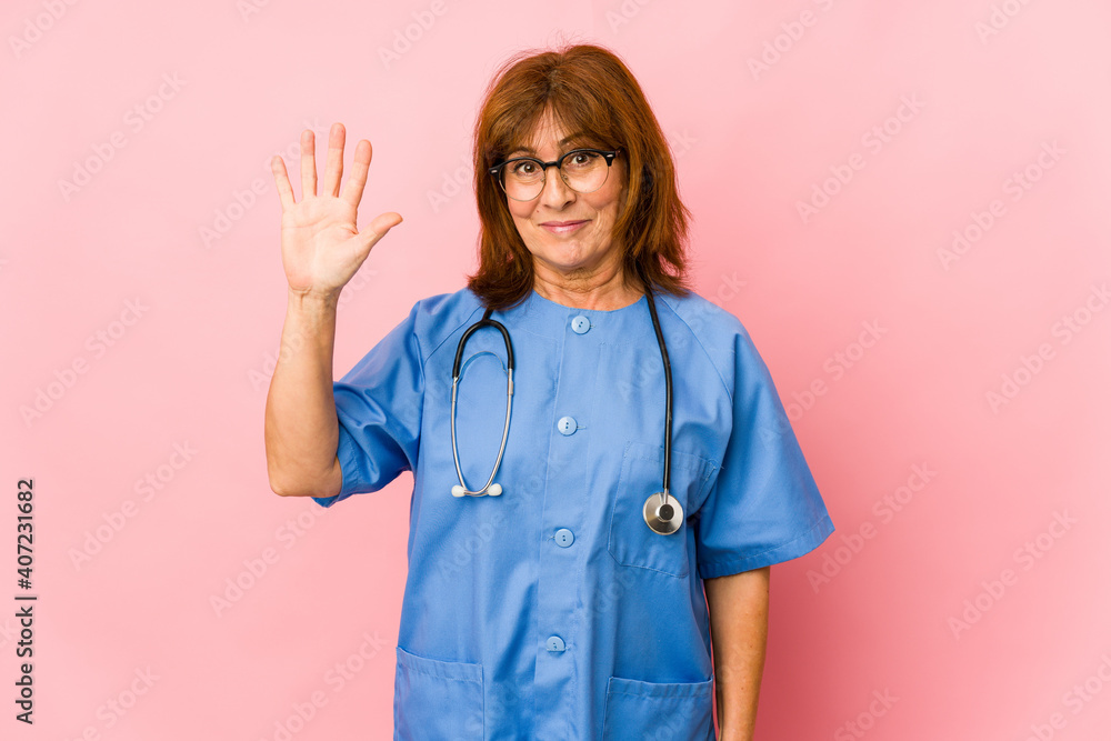 Middle age caucasian nurse woman isolated smiling cheerful showing number five with fingers. Middle age caucasian nurse woman isolated smiling cheerful showing number five with fingers.