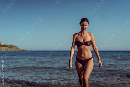 Beautiful young woman in bikini on vacation swimming in sea and enjoying in sand beach. Happy female enjoying summer time holiday on beach. © Vladimir Borovic