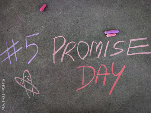 The inscription text on the grey board, #5 Promise day with hand drawn symbol . Using color chalk pieces. Valentines week