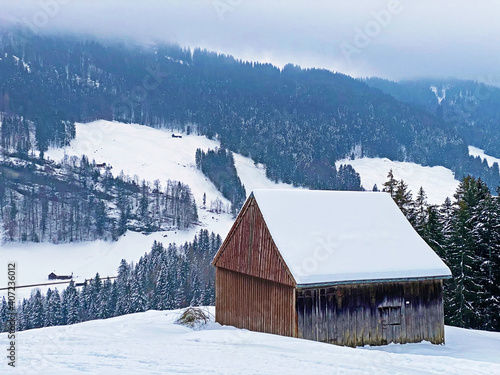 Idyllic Swiss alpine mountain huts dressed in winter clothes and in a fresh snow cover on slopes on the Alpstein mountain range, Ennetbühl or Ennetbuehl - Canton of St. Gallen, Switzerland (Schweiz) photo