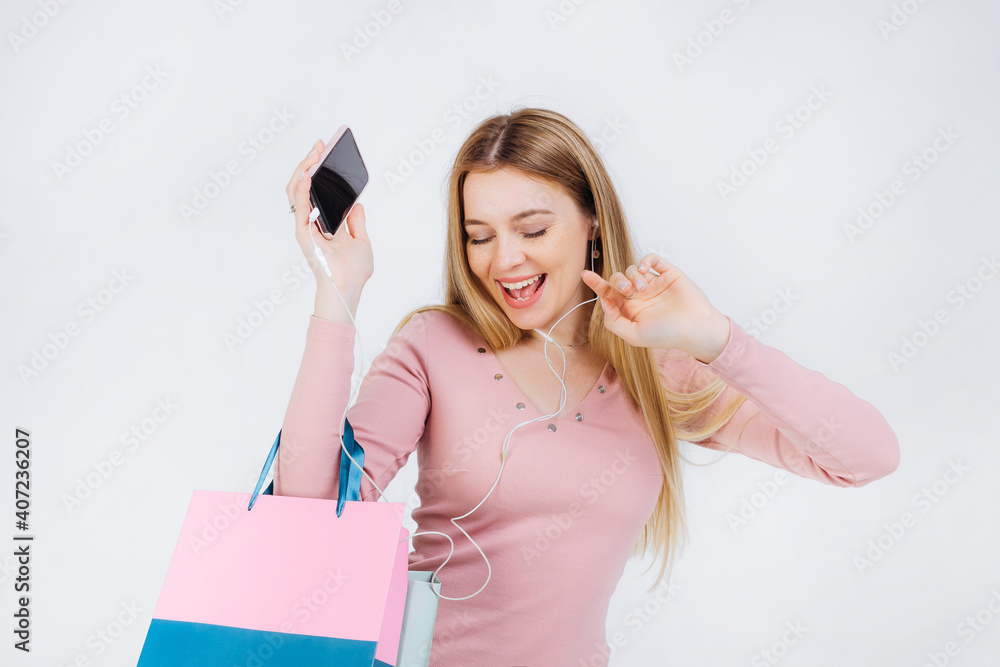 Smiling girl enjoying her favorite song and dancing. Close-up of an excited curly young woman having fun in headphones with a phone. Smiling girl enjoying her favorite song and dancing. Close-up of an excited curly young woman having fun in headphones with a phone.