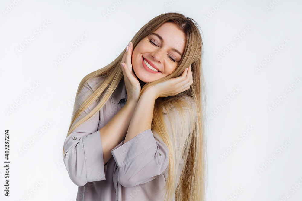 portrait of a relaxed woman smiling tenderly, showing perfect teeth, standing in a shirt on a gray background. portrait of a relaxed woman smiling tenderly, showing perfect teeth, standing in a shirt on a gray background.