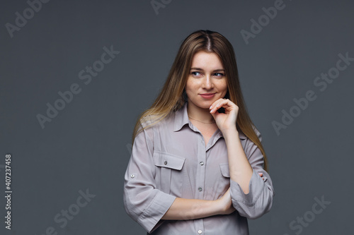 Millennial sad pensive woman touching her chin, looking to the side, feeling upset isolated on gray background, frustrated resentful pouting girl bored.
